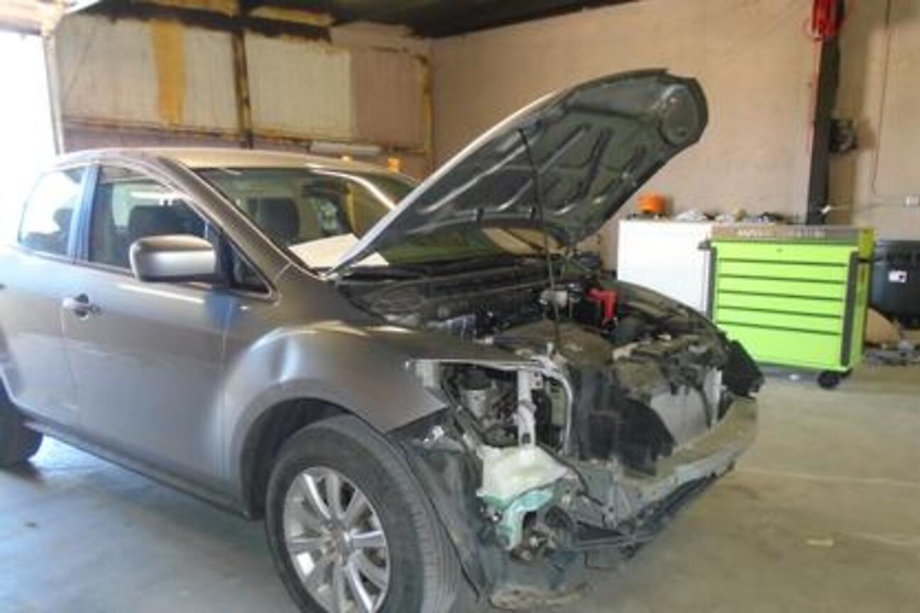 A vehicle being disassembled for repair in the shop bay